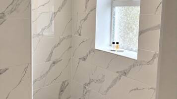 A bathroom with marble tiles, a window with a view, and a black sink.