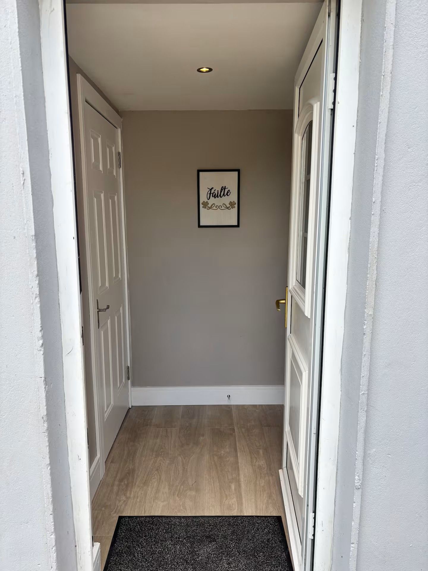 Een gang met een deur links, een deur rechts en een bord met een lijst aan de muur.
