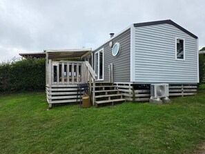 A mobile home with a deck, a chimney, and a utility box. - 5-Star Houlgate Campground - 2-bedroom, 4-person mobile home with AC, facing the pool. 1.5 km from the beach (houlgate)