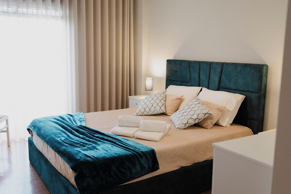 A neatly made bed with a teal headboard, white pillows, and a teal throw blanket.