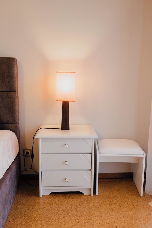 Une petite chambre à coucher, bien rangée, avec une seule table de chevet, une lampe et un lit.