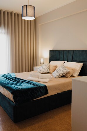 A modern hotel room with a large bed, a dark headboard, and a hanging light fixture.