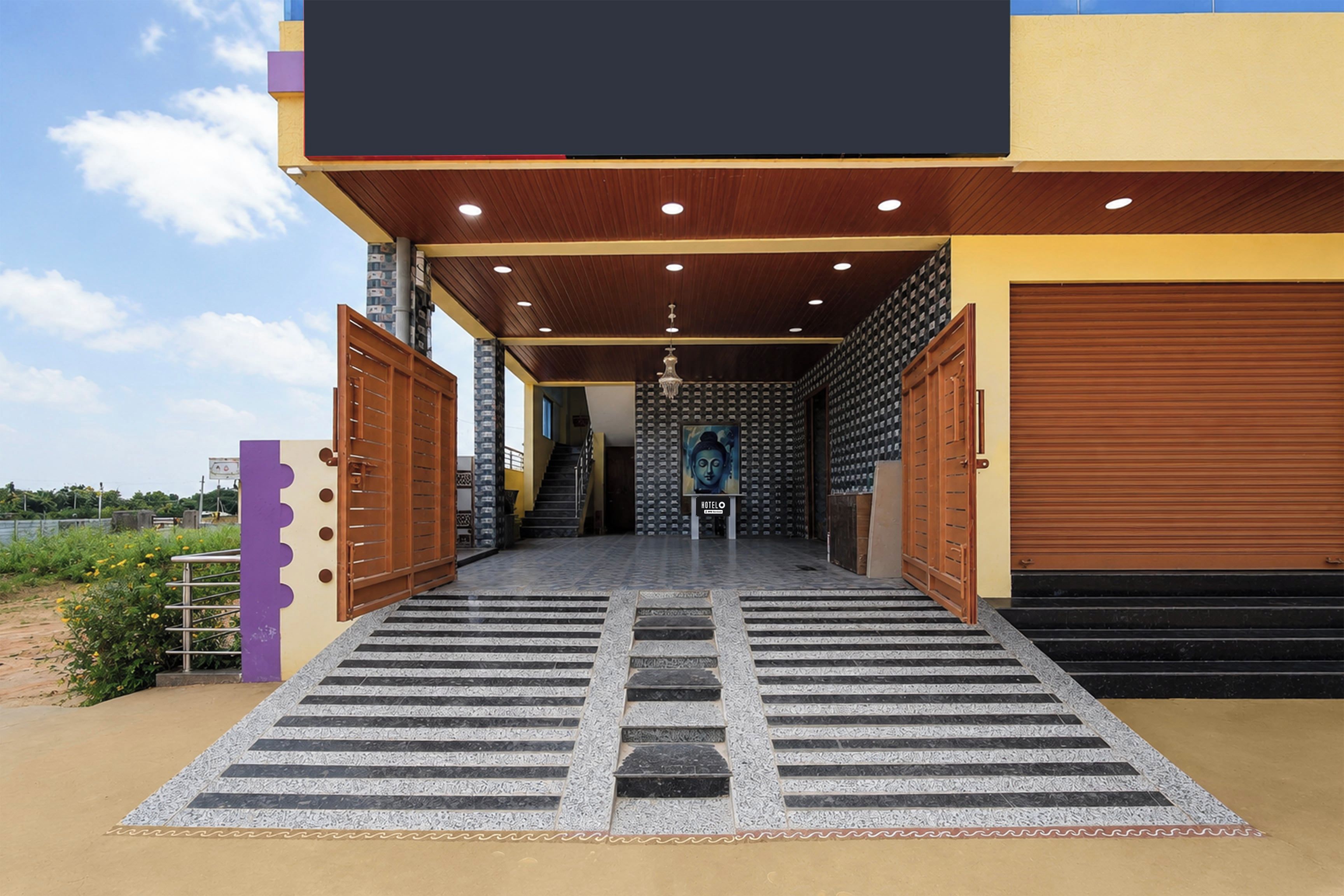 A modern building with a covered entrance, a staircase leading to the interior, and a view of the sky.