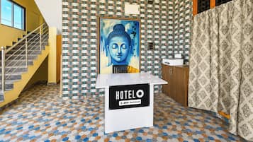 A hotel reception area with a Buddha painting, a staircase, and a patterned floor.