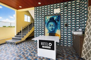 A hotel reception area with a staircase, a Buddha painting, and a sign indicating it is a hotel.
