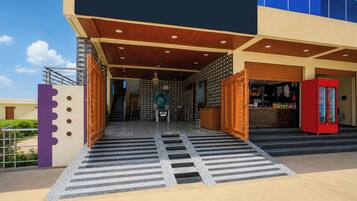 A hotel entrance with a wooden ramp, a reception desk, and a red vending machine.