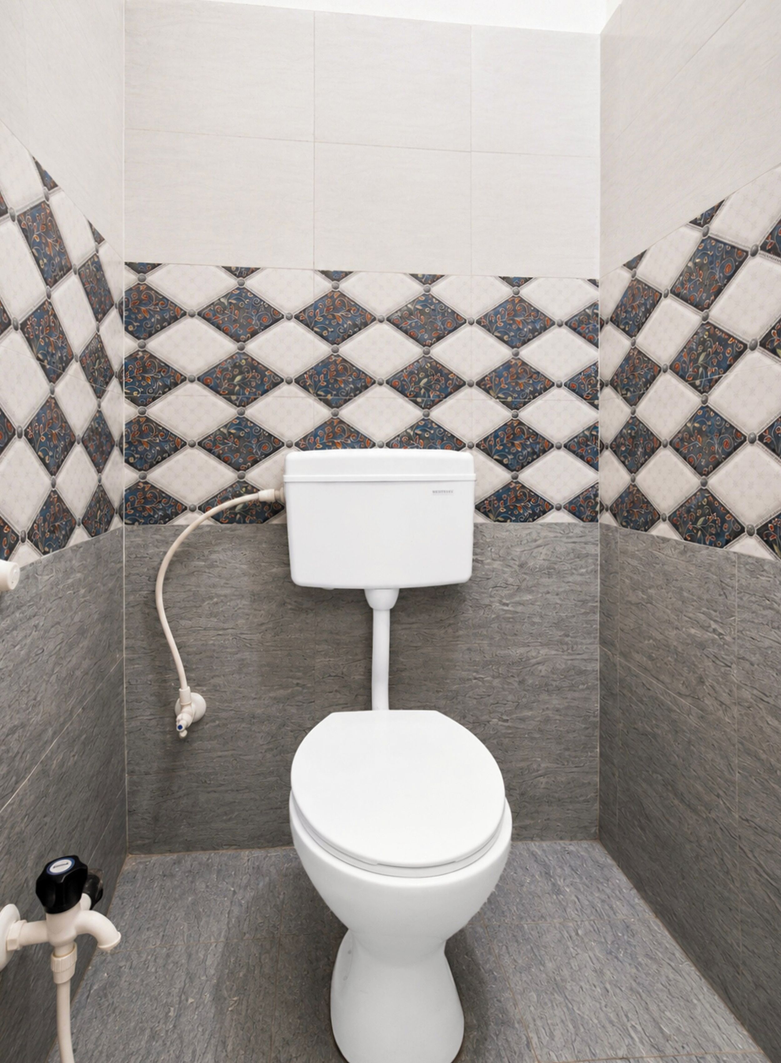 A bathroom with a toilet, a wall-mounted sink, and a patterned tile backsplash.