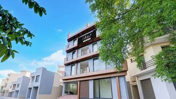 Un edificio de varios pisos con un diseño arquitectónico moderno, que cuenta con balcones y amplias ventanas.