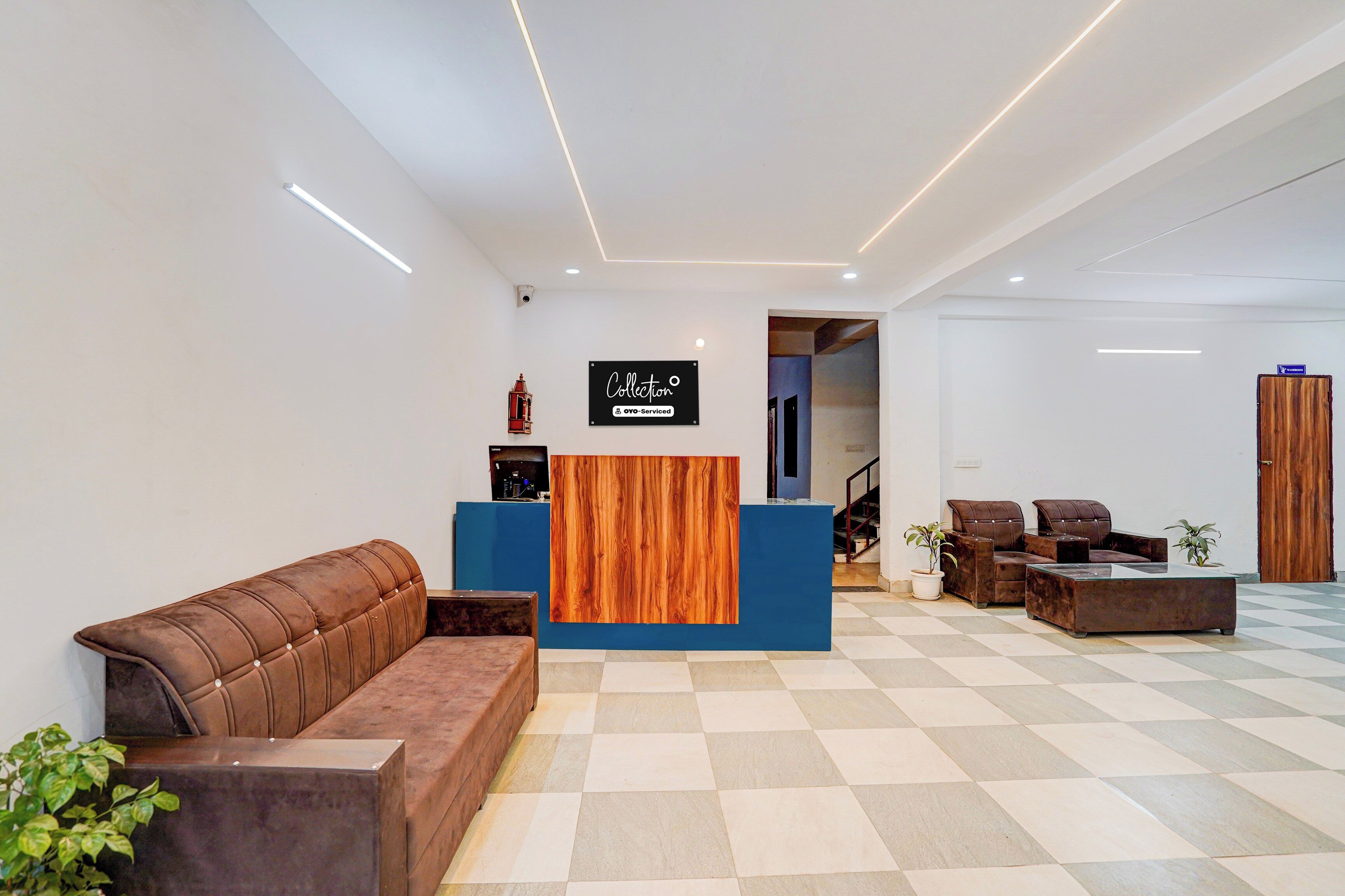 Zona de recepción con mostrador de madera, sofá de cuero marrón y piso a cuadros.