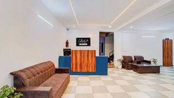 Zona de recepción con mostrador de madera, sofá de cuero marrón y piso a cuadros.