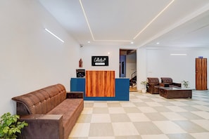 A reception area with a wooden reception desk, a brown leather sofa, and a checkered floor. - Collection O Toll Plaza Kherki Daula (Gurugram)