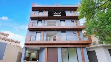 Un hotel de varios pisos con un diseño moderno, que cuenta con balcones en cada planta, ventanas amplias y un letrero que indica que ofrece servicio completo.