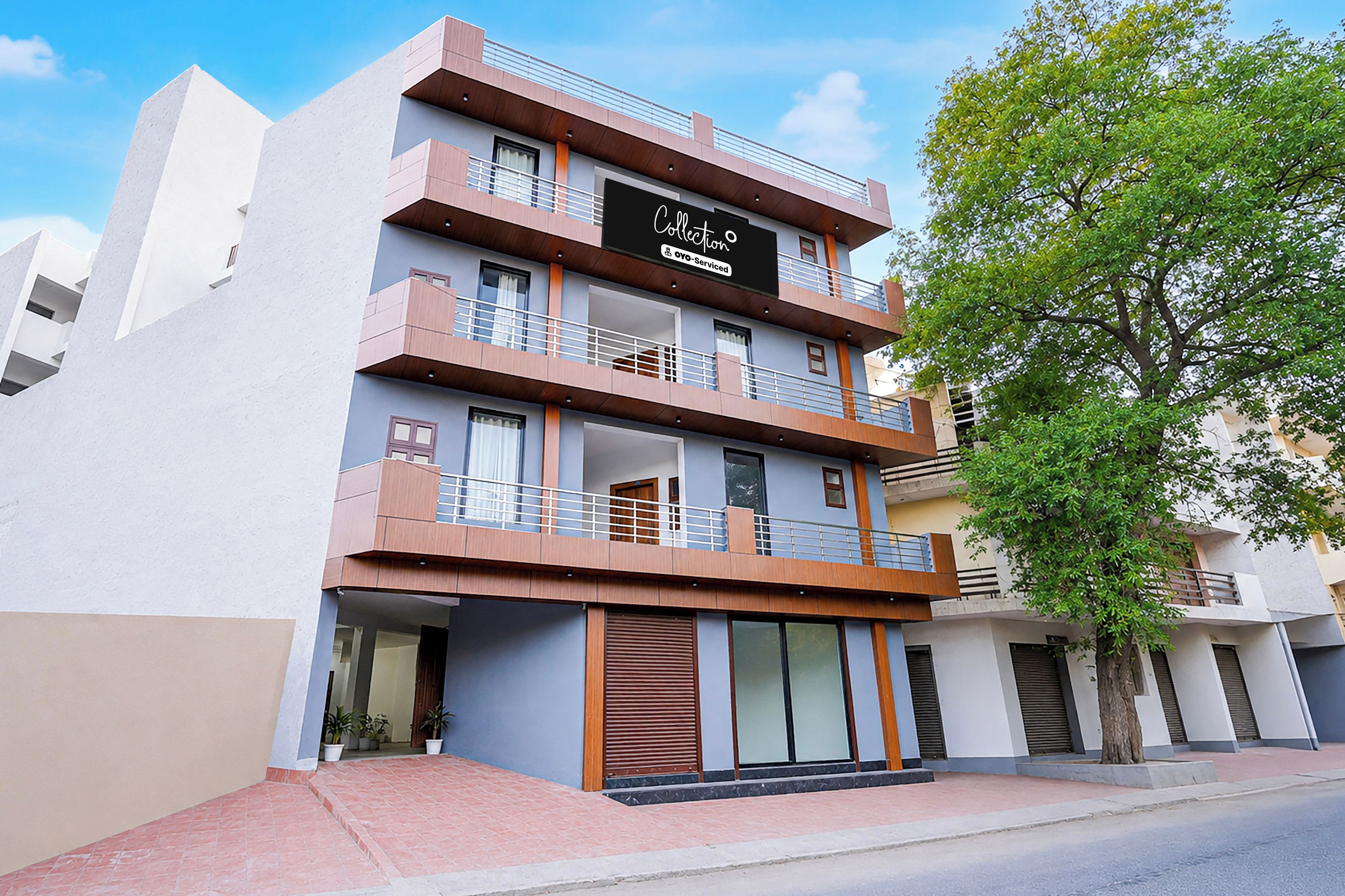 A multi-story building with balconies, large windows, and a sign indicating it is serviced by OYO.