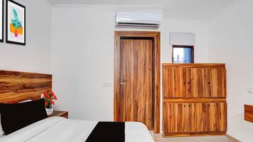 Un dormitorio con cama, armario de madera, equipo de aire acondicionado y una ventana pequeña.
