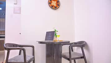 Una habitación con dos sillas, una mesita con una computadora portátil, una planta en maceta y un plato decorativo en la pared.