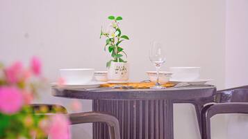 Mesa de jantar redonda com um vaso de flores brancas, duas tigelas brancas, um copo e um prato com comida.