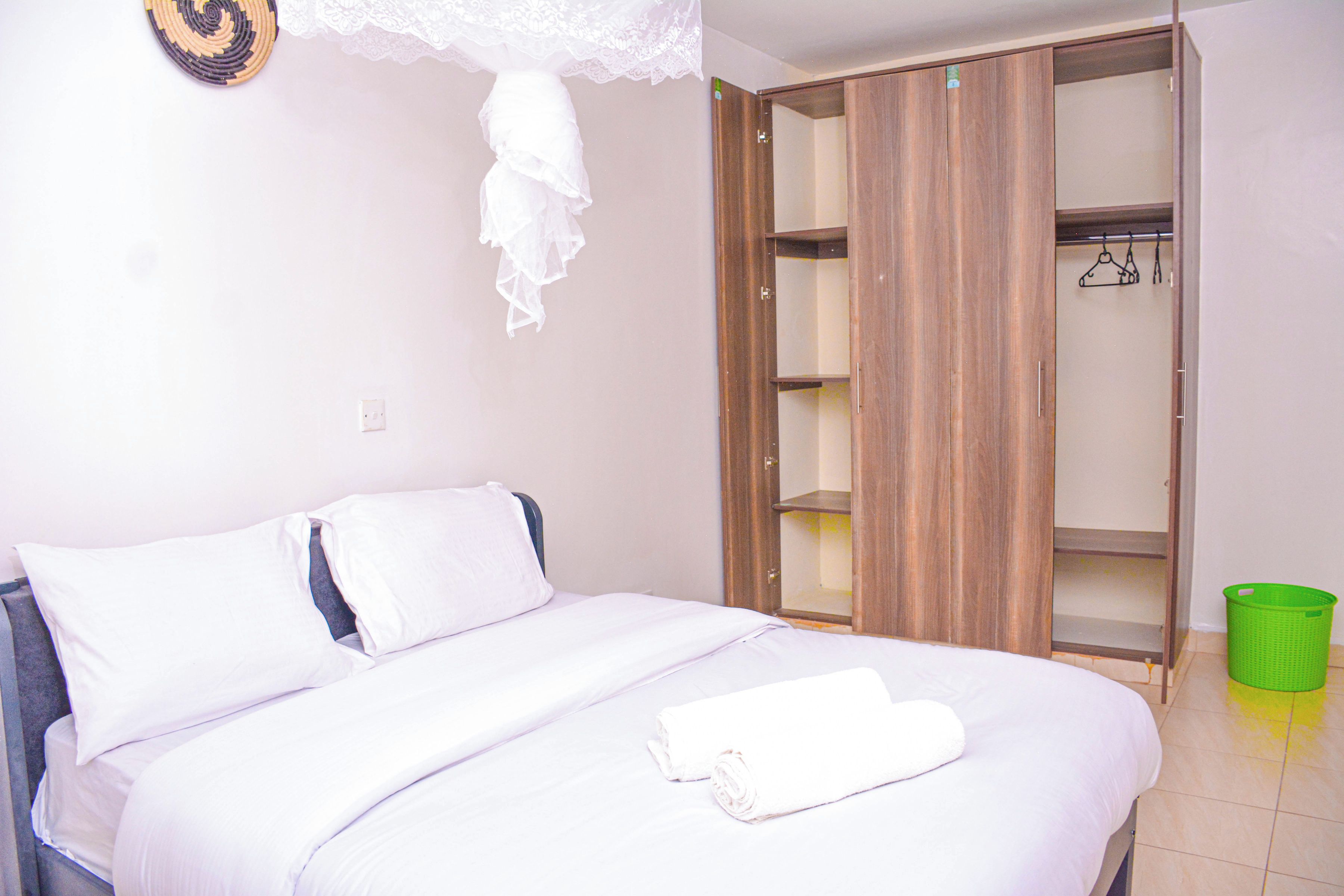 Un dormitorio con cama, armario y una cesta verde para la ropa.