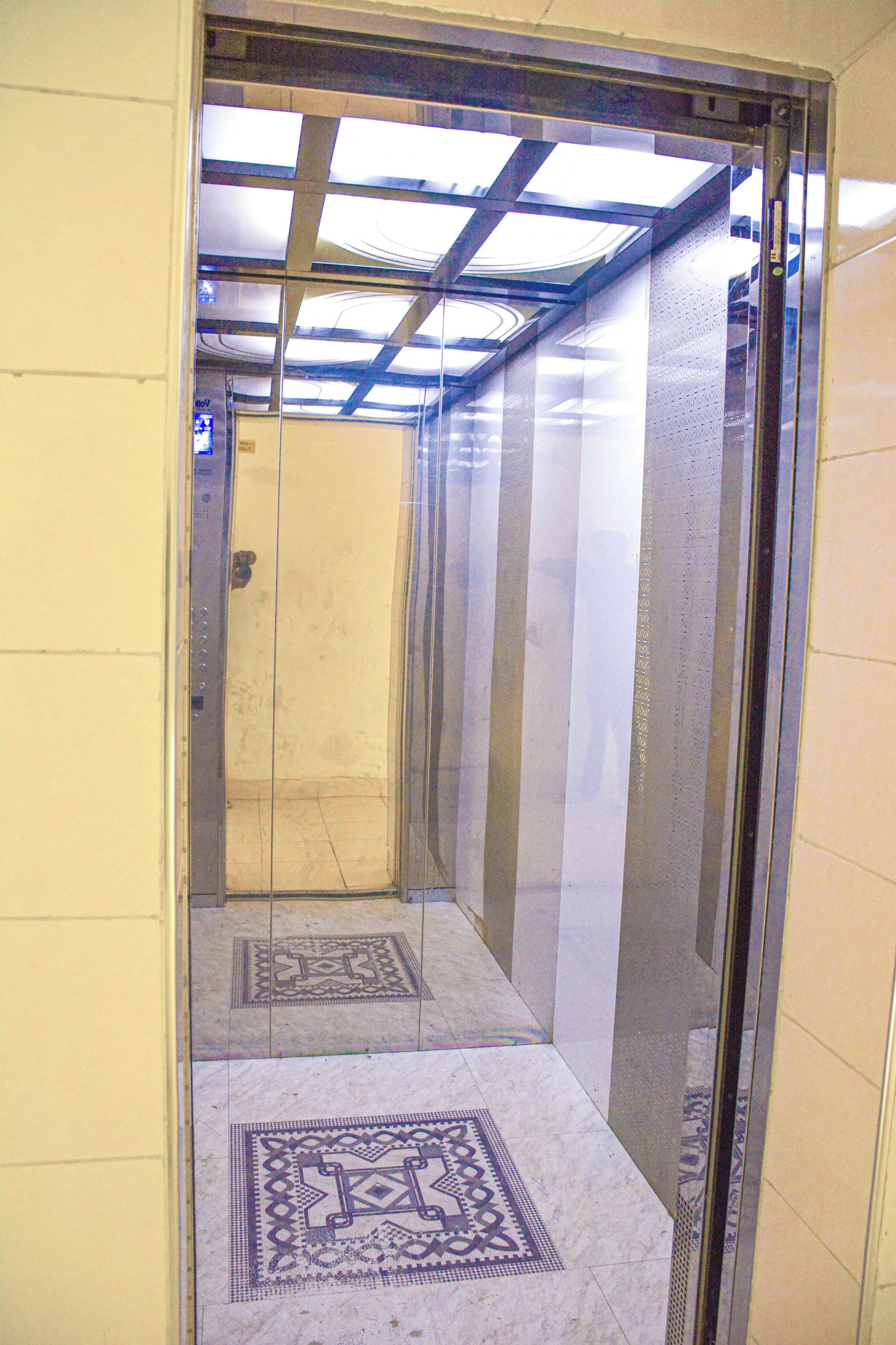 Een lift met een patroon vloer, glazen wanden en een plafond met dakramen.