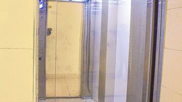 Um elevador com piso estampado, paredes de vidro e teto com claraboias.