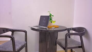 A small round table with a laptop, a glass of wine, and a potted plant. Two chairs are positioned around the table.