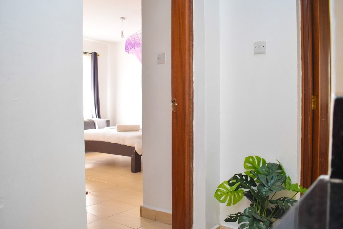 Ein Hotelzimmer mit einem Bett, einer Zimmerpflanze und einer Tür zu einem weiteren Raum.