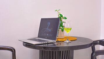 Um laptop sobre uma mesa redonda, com um copo de vinho e um vaso de planta ao lado.