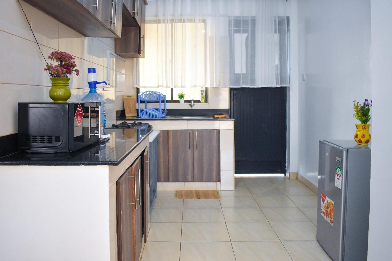 Een kleine keuken met een magnetron, spoelbak en kastjes.