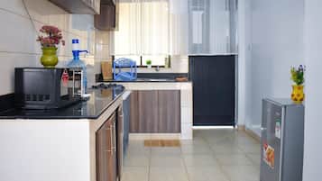 Cocina compacta con microondas, lavamanos y armarios.