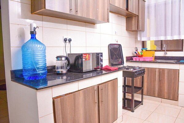 A kitchen with a large water dispenser, a coffee maker, a toaster, a microwave, and a gas stove.