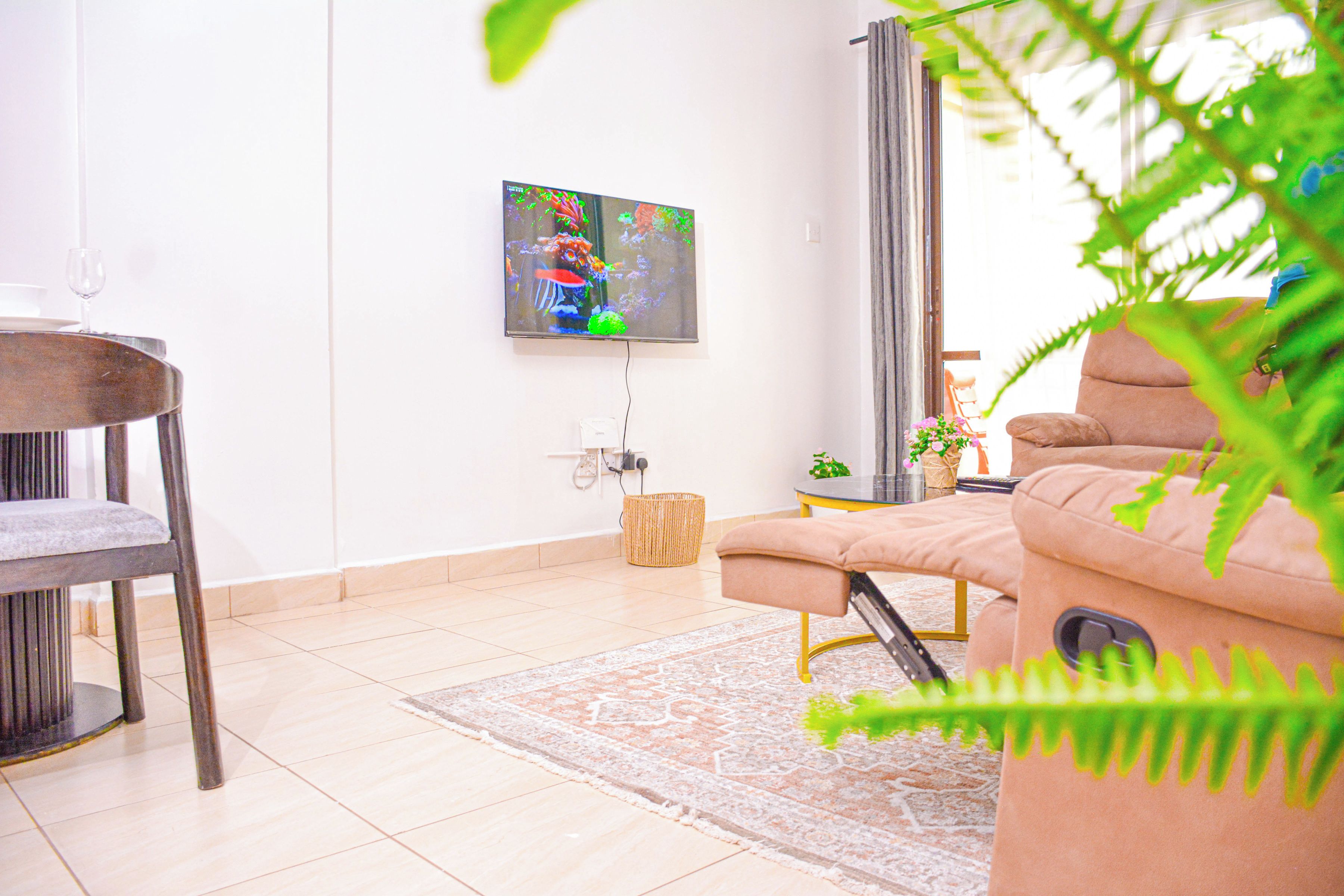 Una sala de estar moderna con un sofá, una butaca, un televisor de pantalla plana montado en la pared y una mesita.