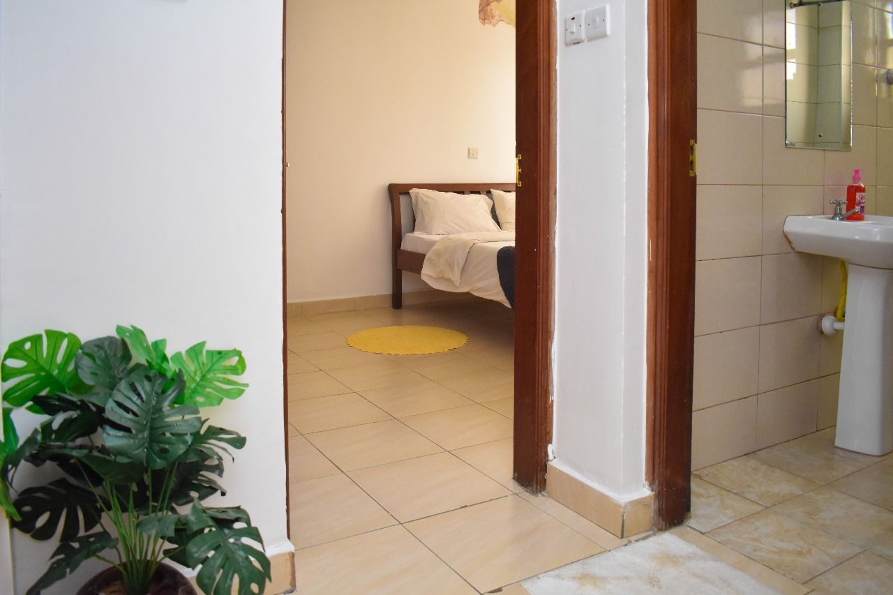 Ein Zimmer mit einem Bett, einem Waschbecken und einem Blumentopf.