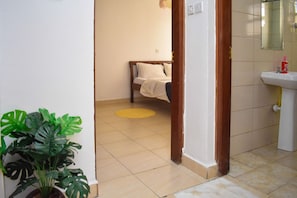Ein Zimmer mit einem Bett, einem Waschbecken und einem Blumentopf.