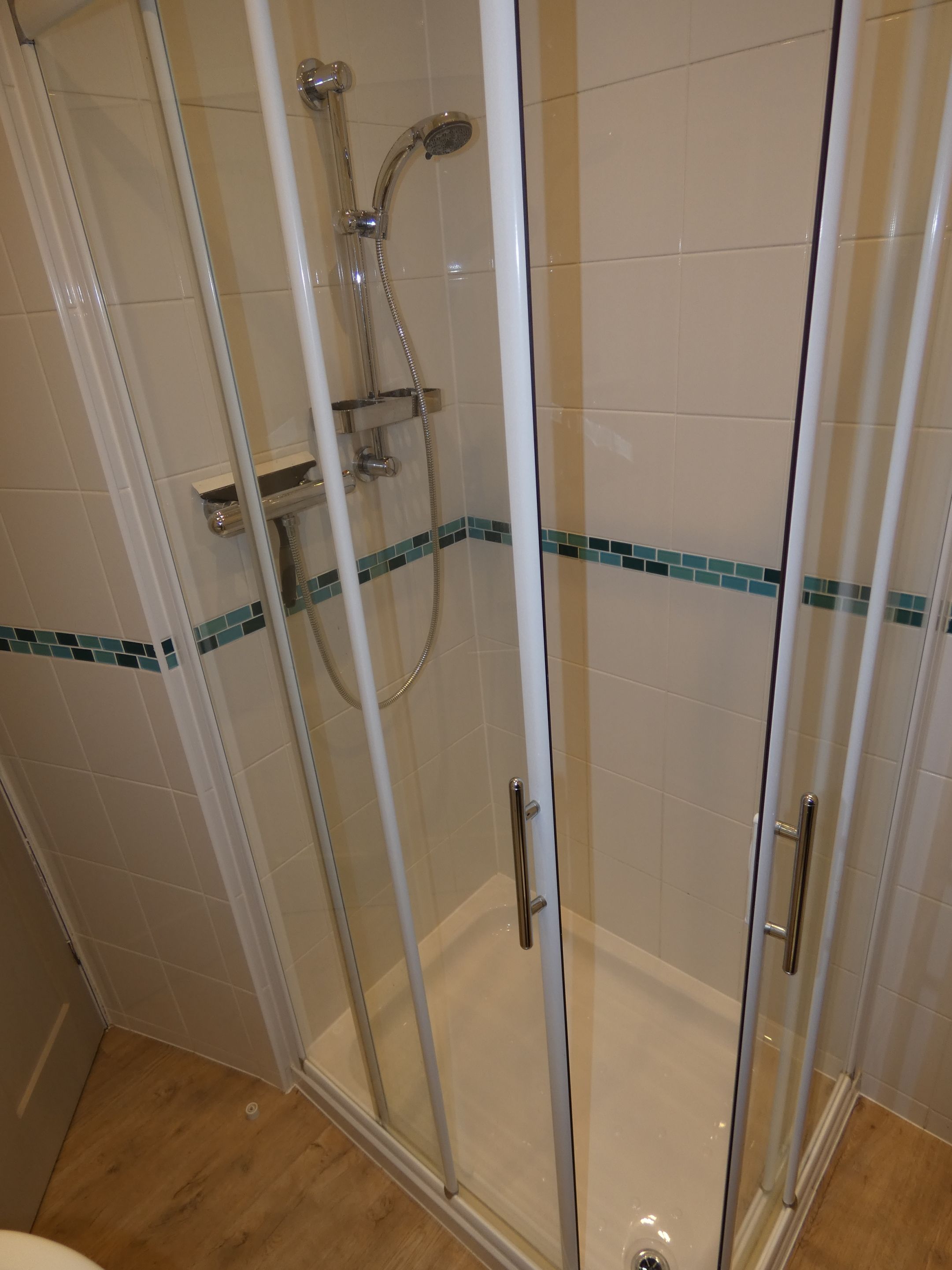 Eine Duschkabine mit Handbrause und Armaturen an der Wand.