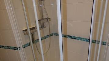 Eine Duschkabine mit Handbrause und Armaturen an der Wand.