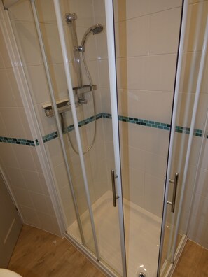 Eine Duschkabine mit Handbrause und Armaturen an der Wand.