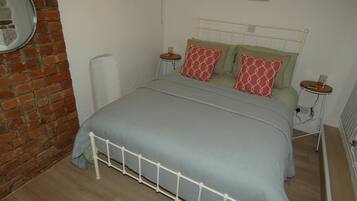 Ein Schlafzimmer mit einem Bett, einer Ziegelwand, einem Heizkörper und einem kleinen Tisch mit einer Lampe.