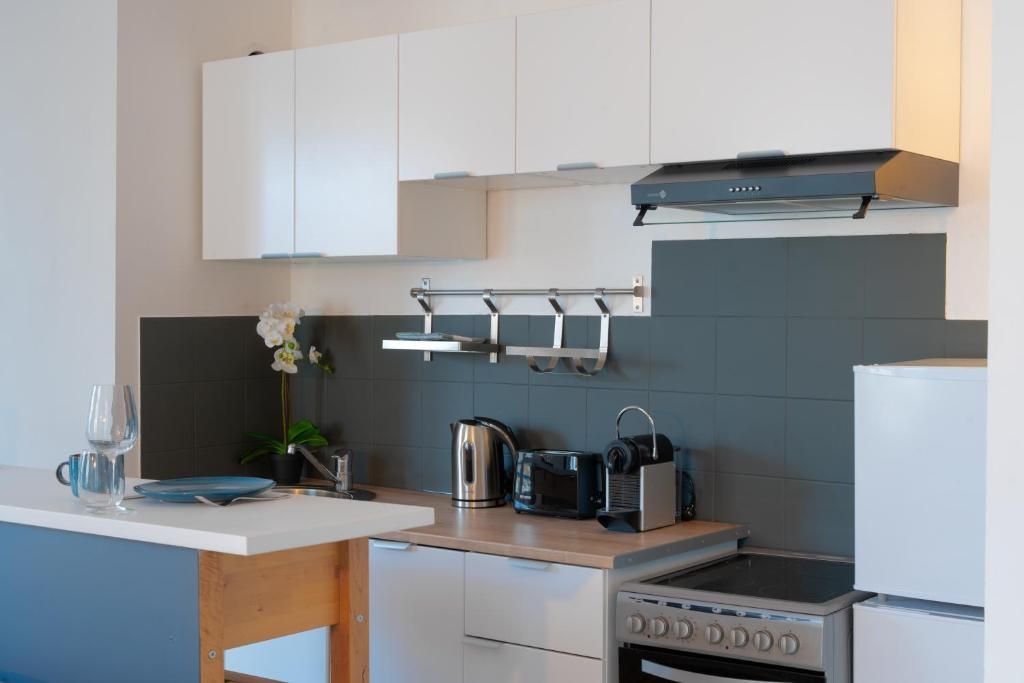 A modern kitchen with white cabinets, a stainless steel kettle, a toaster, and a built-in oven.