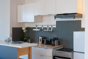 Una cocina moderna con armarios blancos, un hervidor de acero inoxidable, un tostador y un horno empotrado.
