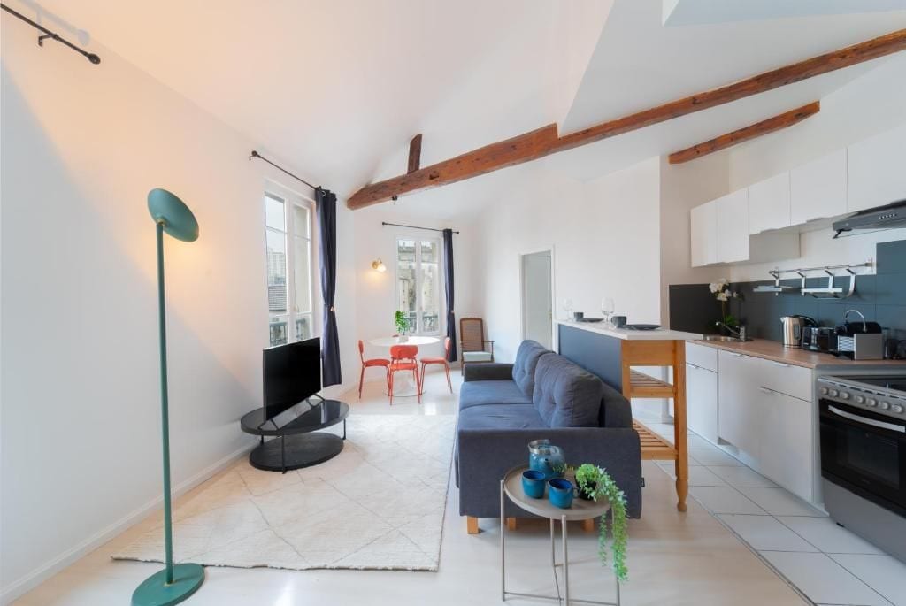 A modern living space with a sofa, a dining table, and a kitchen area.