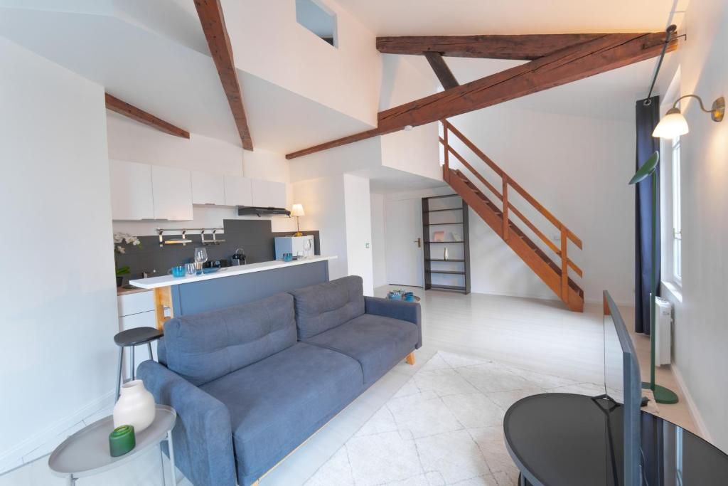 A modern living space with a sofa, a dining area, and a staircase.