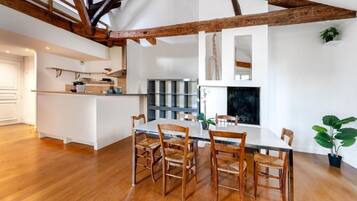 Une cuisine moderne avec des poutres en bois, un coin repas avec une table et des chaises, et une grande fenêtre.
