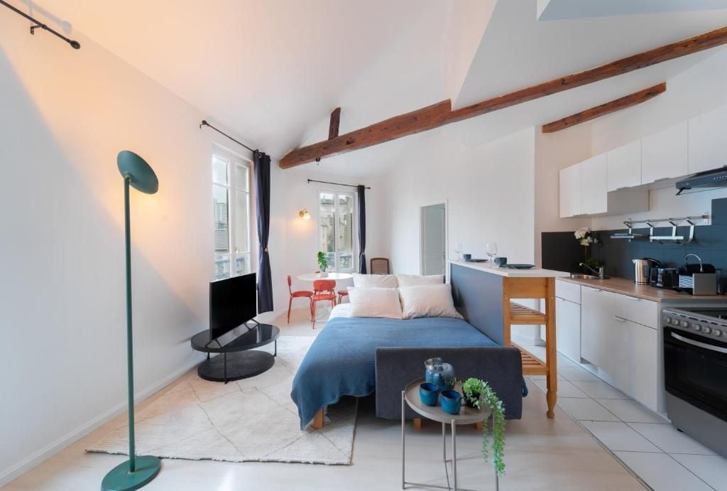 Una habitación pequeña con cama, mesita de noche y vista a la cocina.