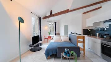 Una habitación pequeña con cama, mesita de noche y vista a la cocina.