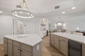 A modern kitchen with a central island, built-in appliances, and a pendant light fixture. - Romar House 1004A by Liquid Life (Orange Beach)