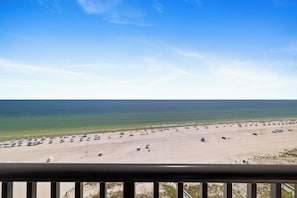 A beach with a clear sky, a sandy shore, and numerous umbrellas. - Romar House 1004A by Liquid Life (Orange Beach)