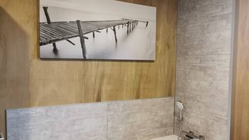 Une salle de bain avec un mur en bois, une grande baignoire et une douche.