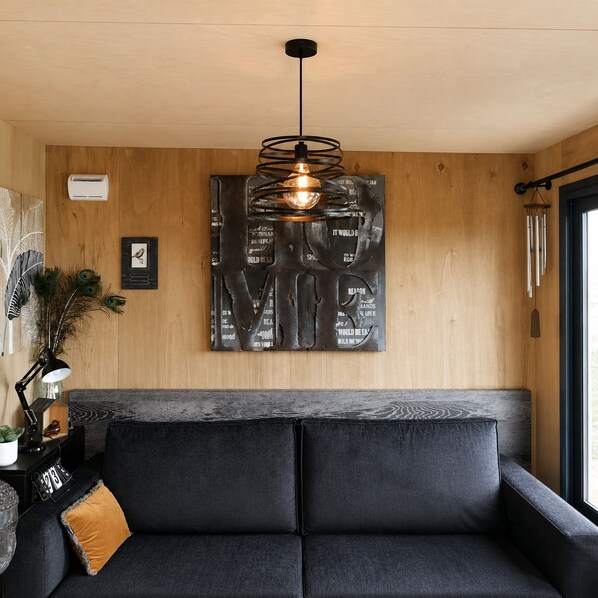 En moderne stue med en mørkegrå sofa, en trævæg og et unikt kunstværk over sofaen.