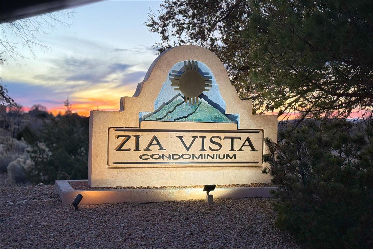 Skilt for ZIA VISTA CONDOMINIUM med et bjergmotiv og en solnedgang i baggrunden.