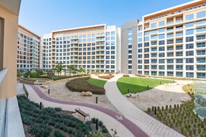 A modern residential building with multiple balconies, a landscaped courtyard with a pathway, and a pool area. - Resort-Living 2BR+Maids and Beach Access, Close to Khor Fakkan Amphitheatre (Khor Fakkan)