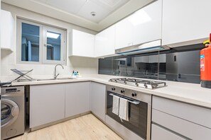 A modern kitchen with a gas stove, oven, sink, and a window with blinds. - Resort-Living 2BR+Maids and Beach Access, Close to Khor Fakkan Amphitheatre (Khor Fakkan)